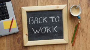 Photo of a desk top with a blackboard saying back to work